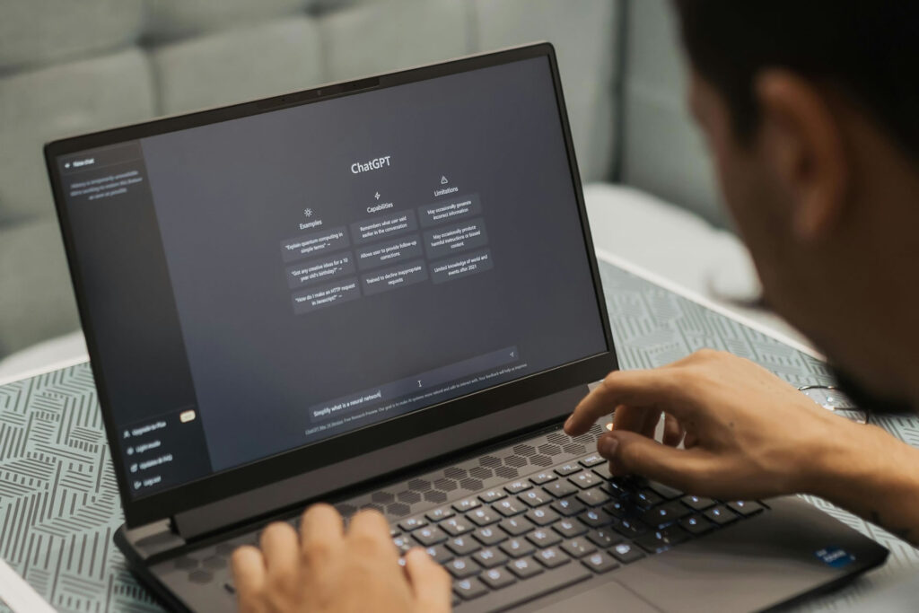 A person focused on typing on a laptop, with a menu displayed on the screen in a well-lit environment.
