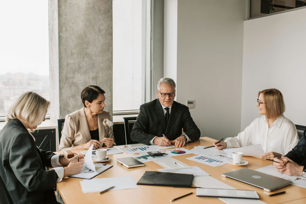 Business professionals in a meeting reviewing charts and reports, discussing firm strategy and performance before ramping up marketing.
